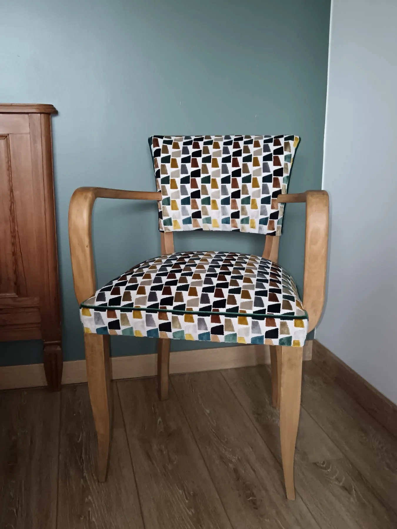 Fauteuil bridge recouvert d’un velours jacquard à motifs géométriques ocre, noir et bleu