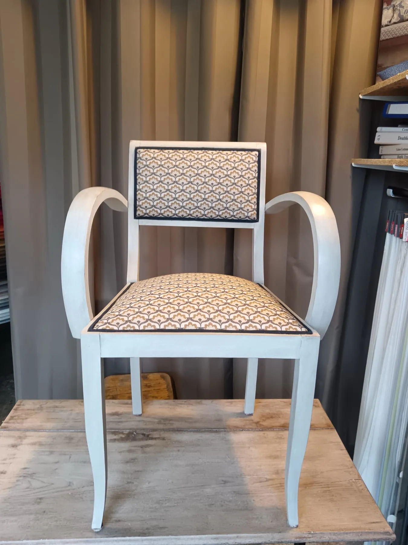 Fauteuil bridge en bois patiné blanc recouvert d’un tissu d’inspiration Art déco bleu et sable