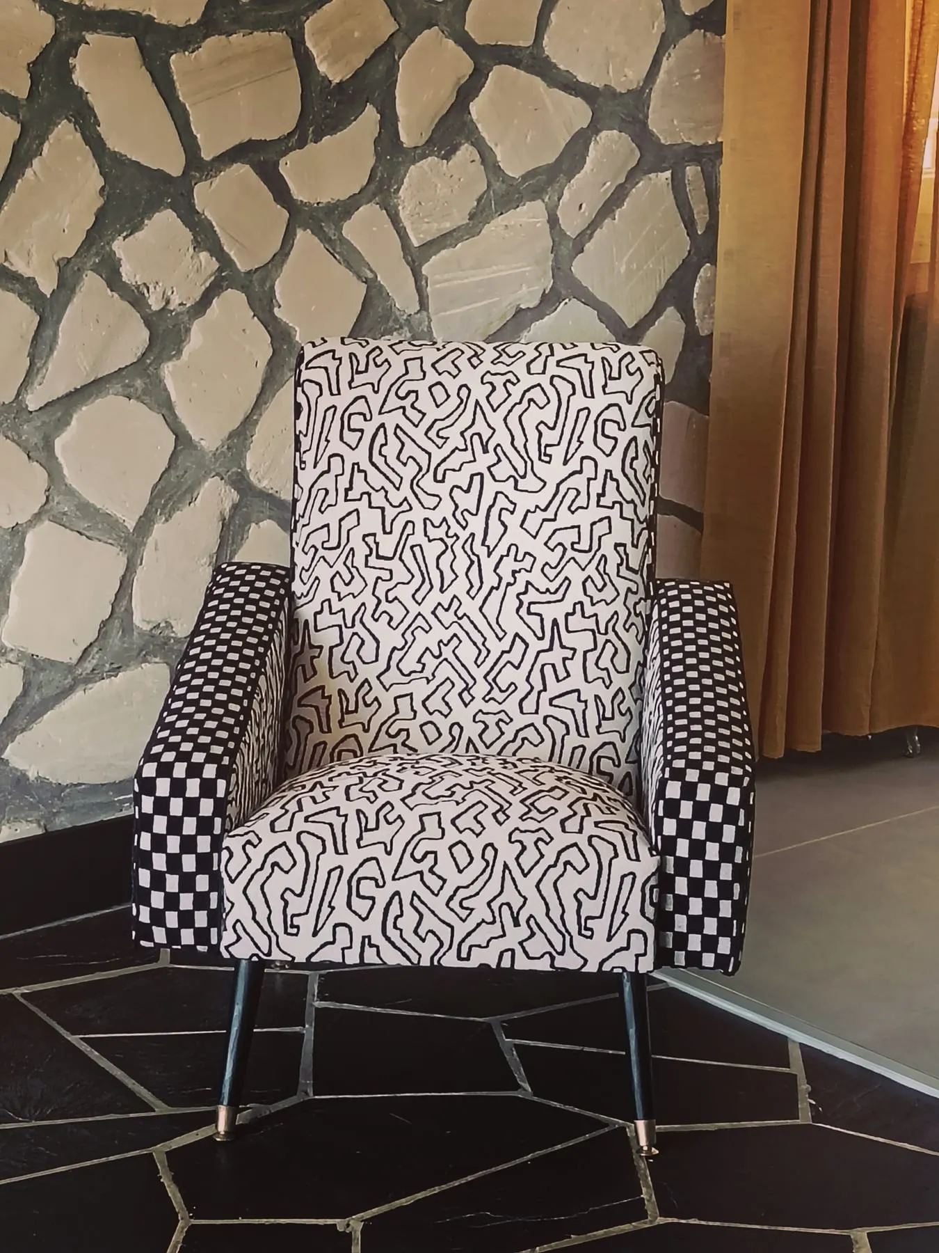 Fauteuil recouvert d’un imprimé graphique noir et blanc avec accoudoirs à damier