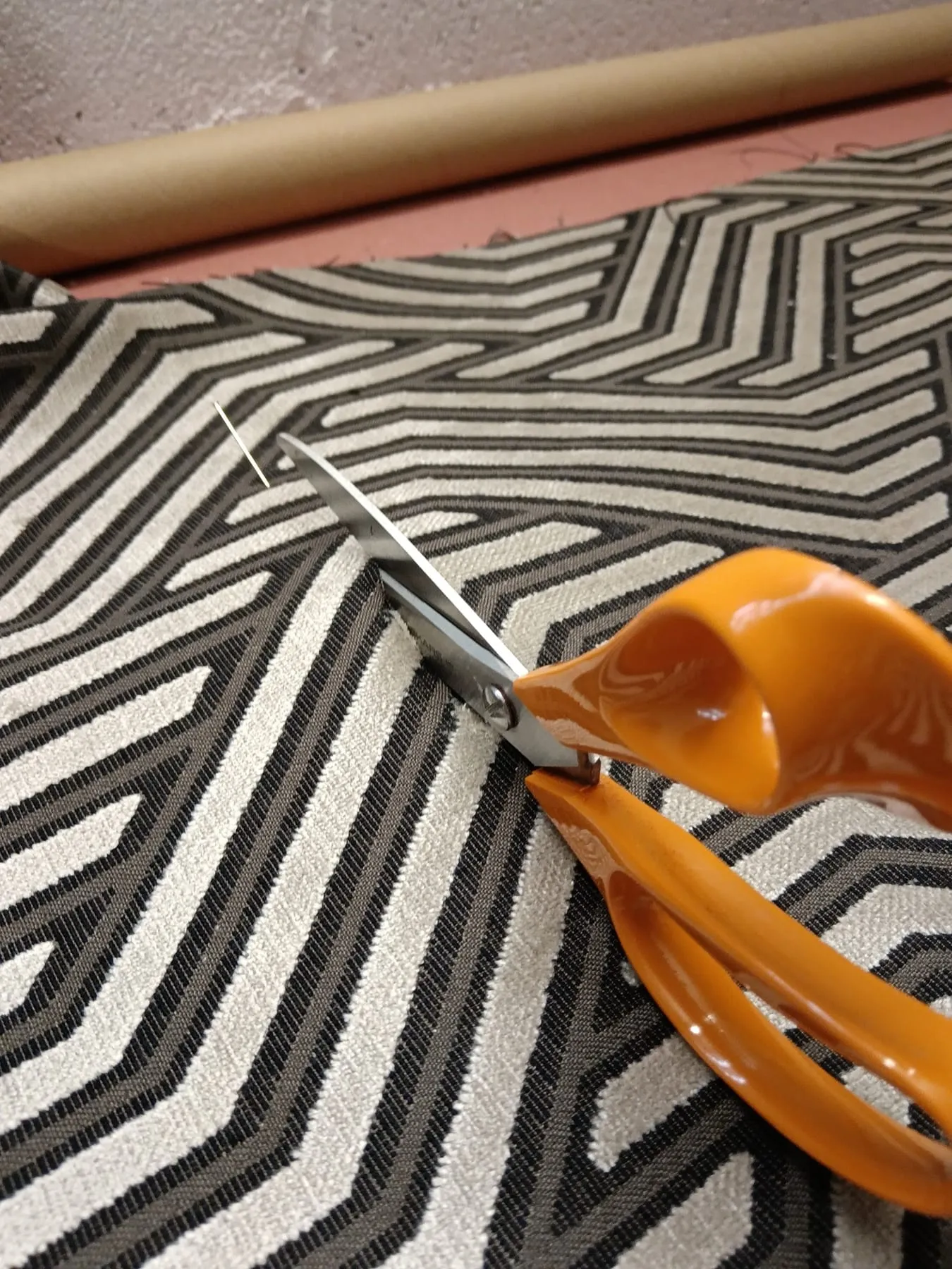 Coupe d’un tissu graphique aux ciseaux de tapissier
