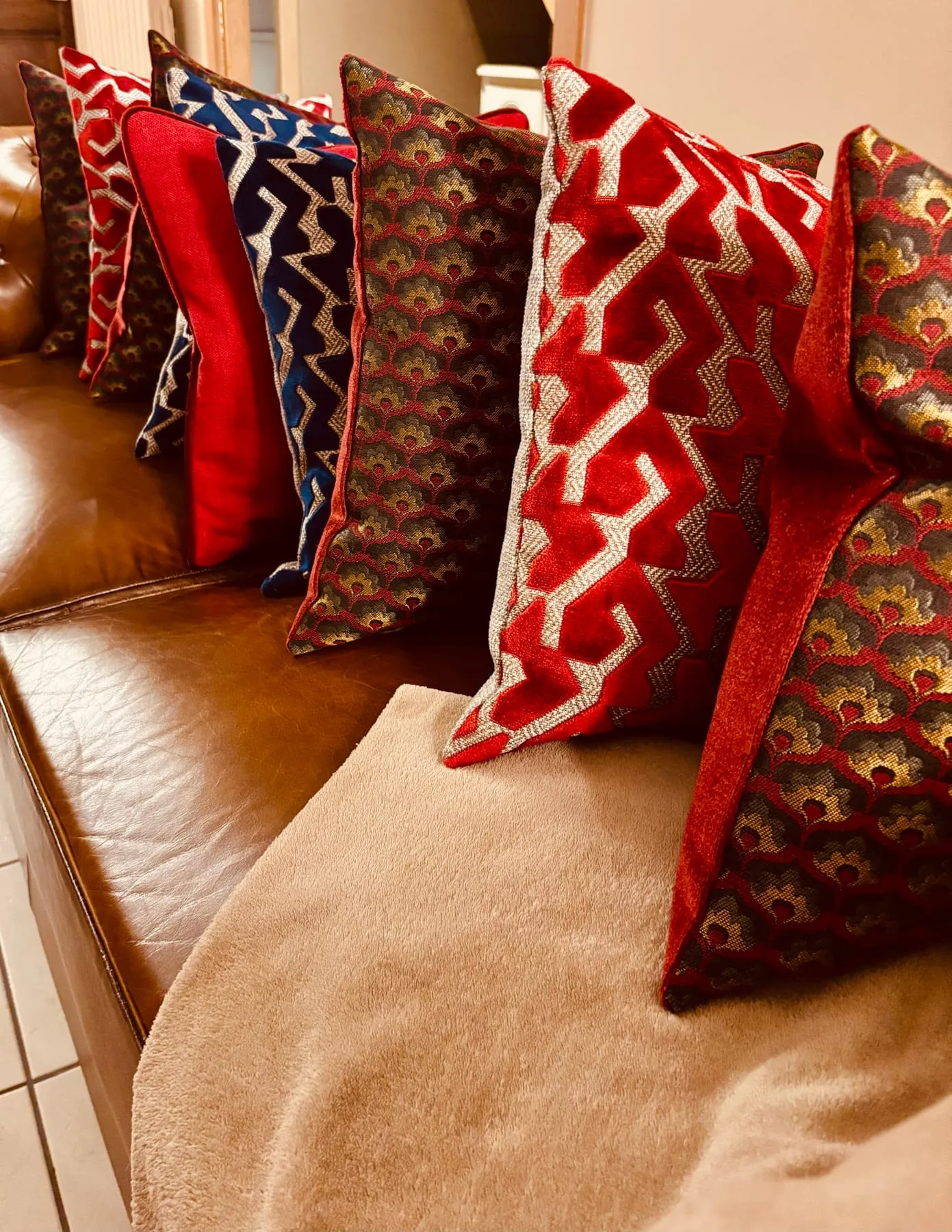 Ensemble de coussins en jacquard rouge et bleu posés sur un canapé de cuir