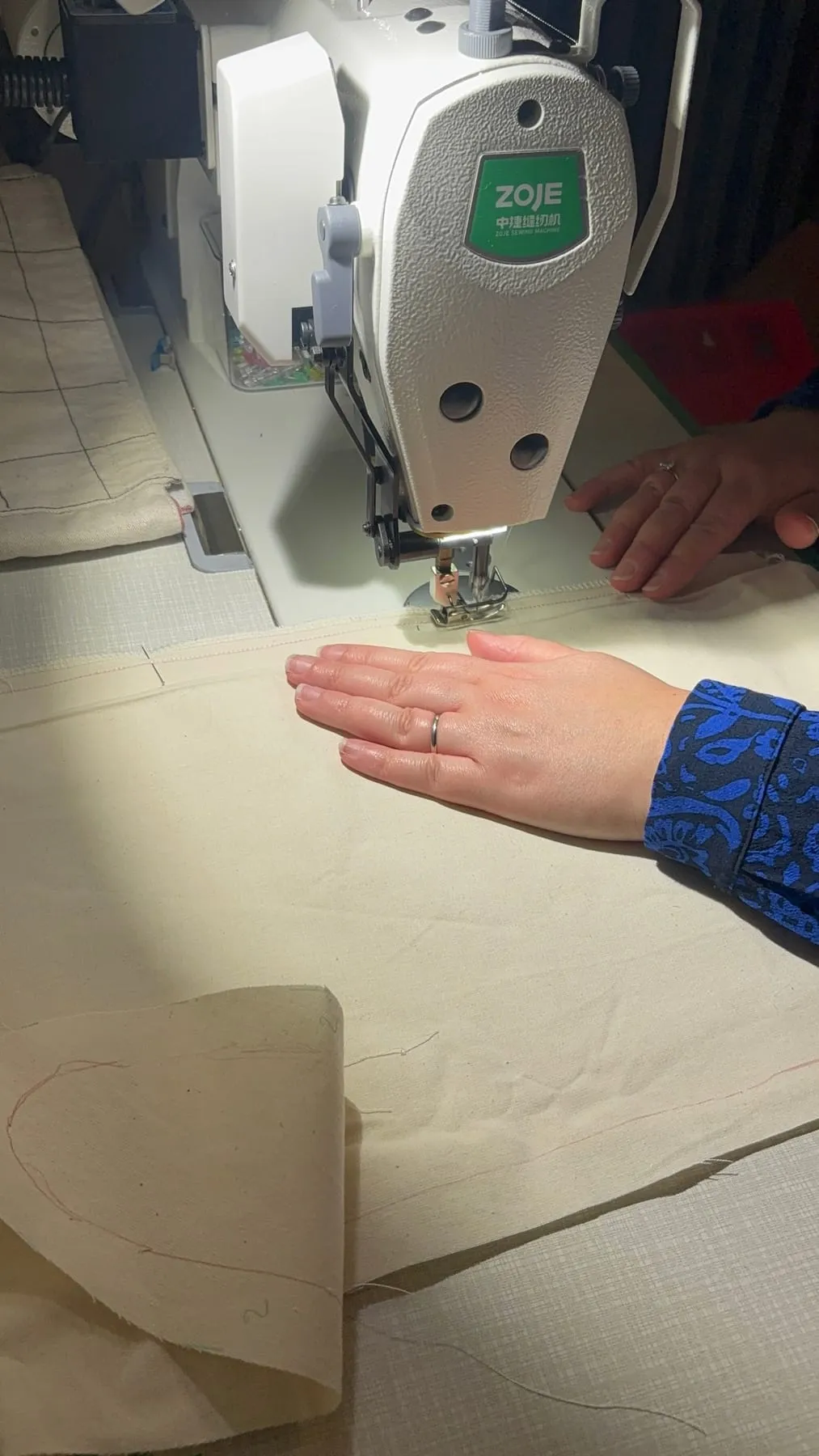 Mains guidant un tissu sous le pied de la machine à coudre