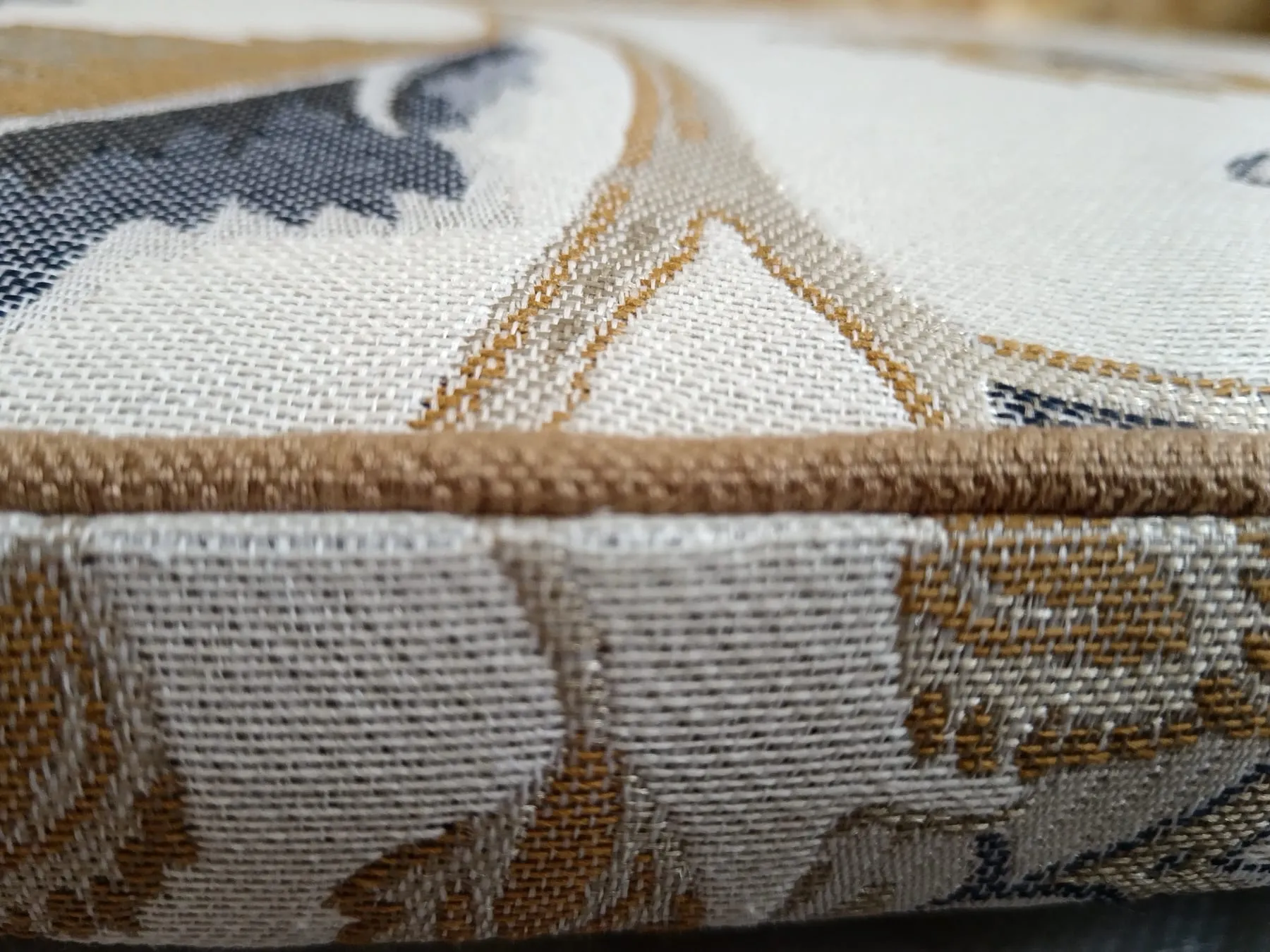 Gros plan du double passepoil et du tissu d’inspiration Art déco sur le dossier du fauteuil