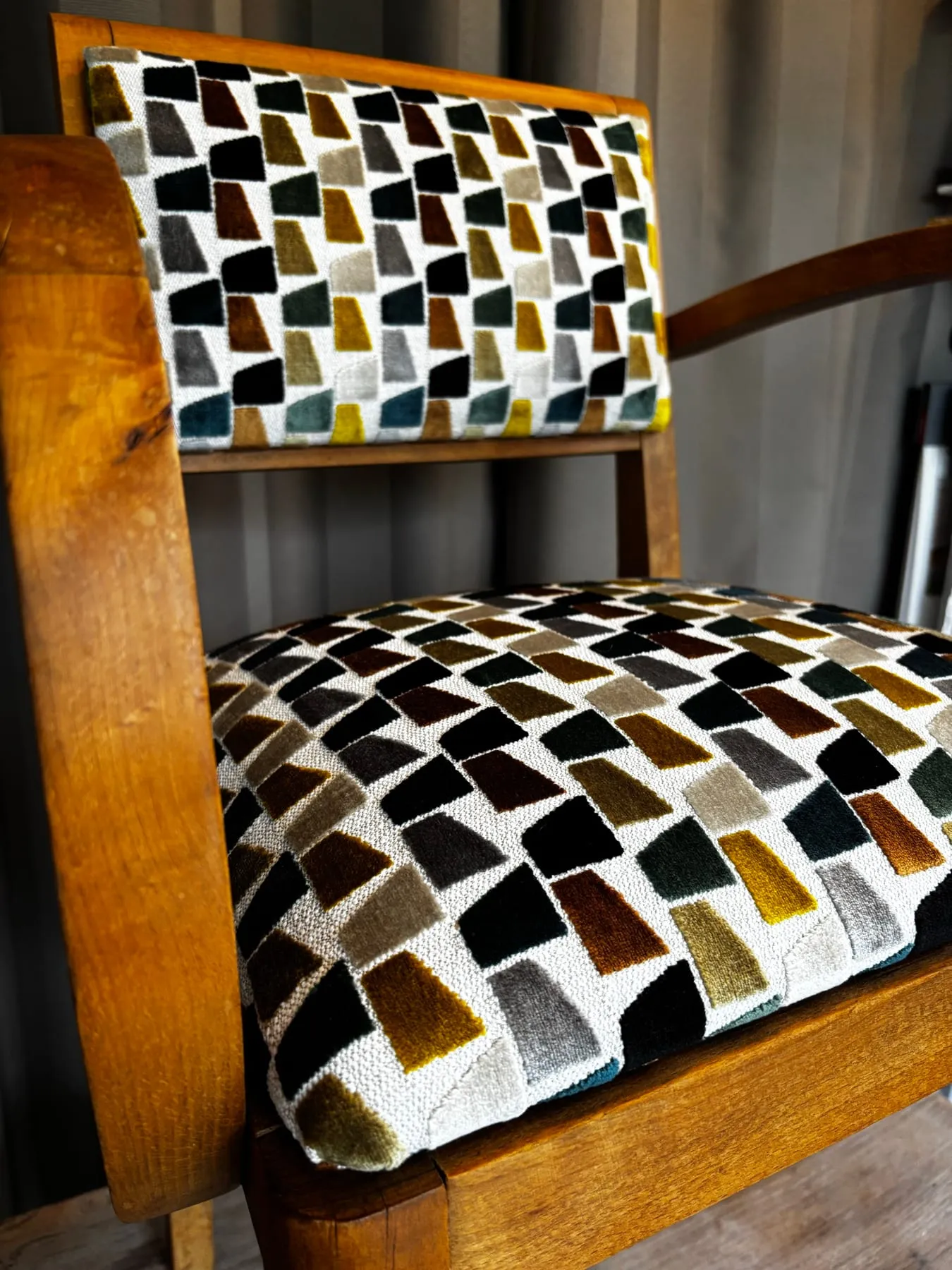 Gros plan du velours jacquard à motifs géométriques sur l’assise du fauteuil bridge