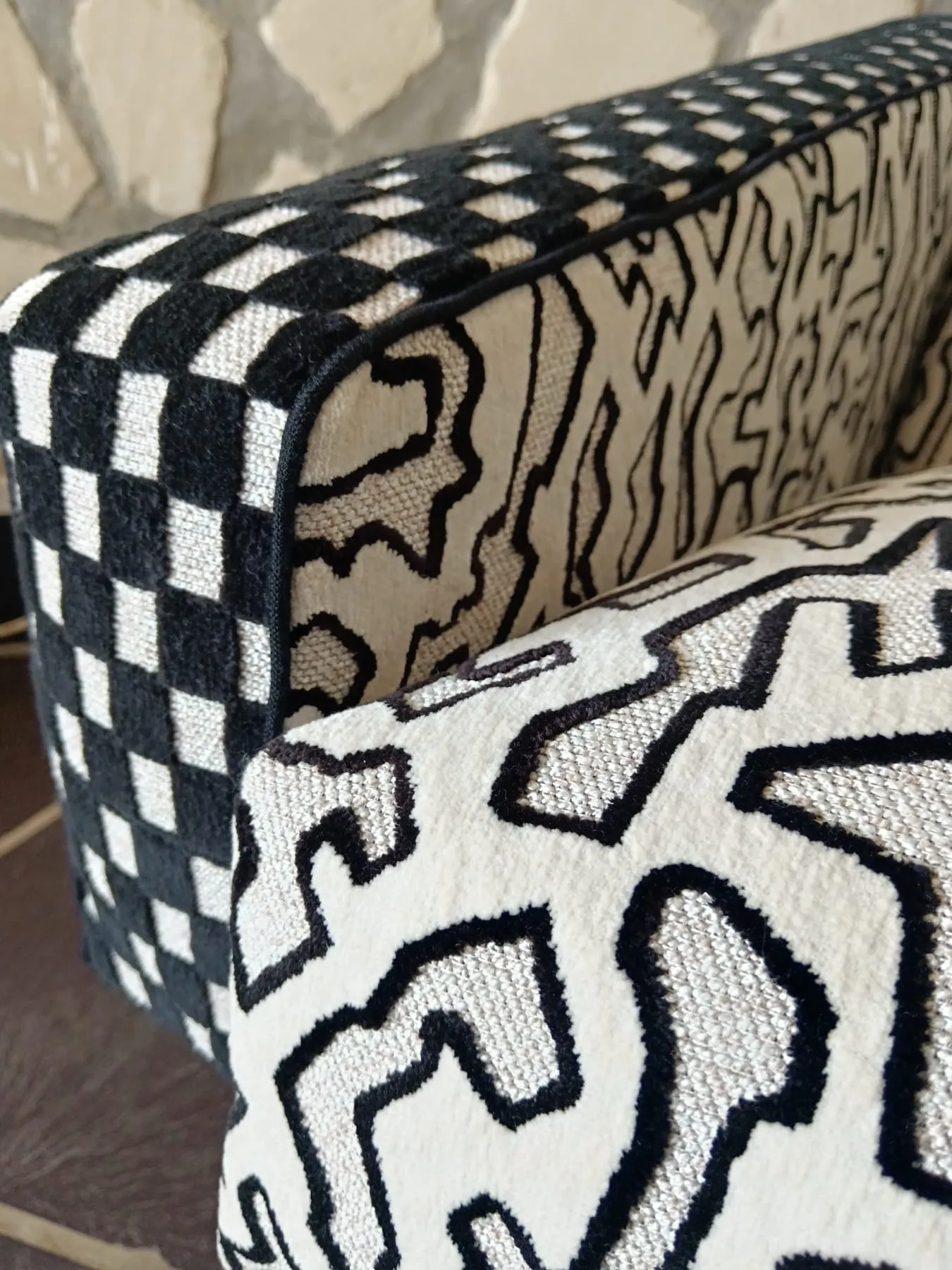 Gros plan du velours jacquard à damier et du motif graphique sur le dossier du fauteuil