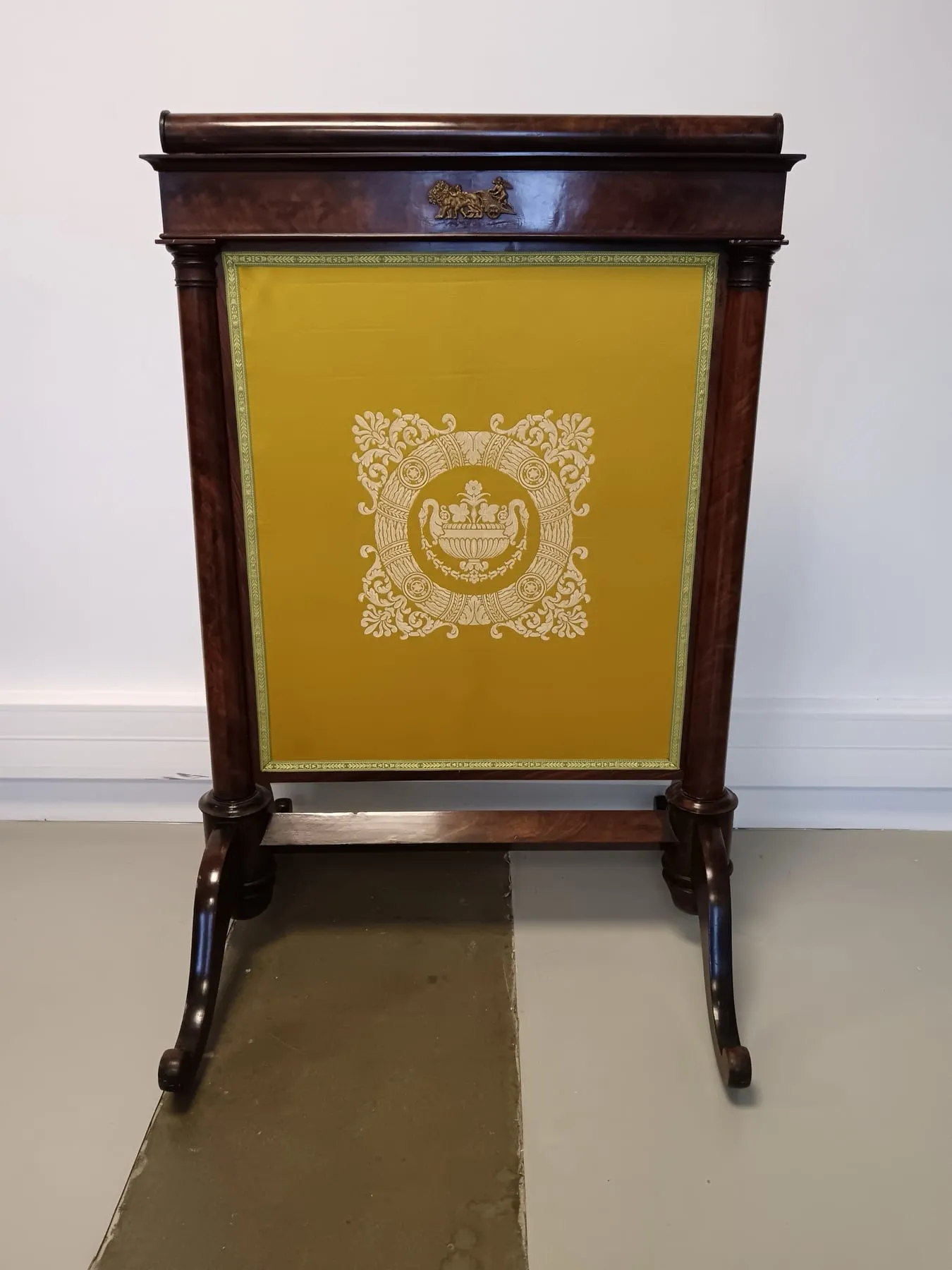 Écran de cheminée Empire en acajou, panneau tendu d’une soie jaune à motif centré et passementerie coordonnée