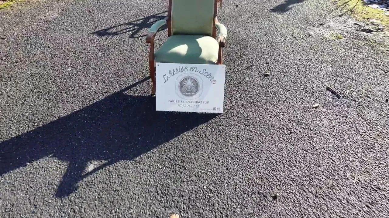 Vue aérienne d’un fauteuil restauré et de l’enseigne de l’atelier, posés dans une rue de Mons-en-Laonnois