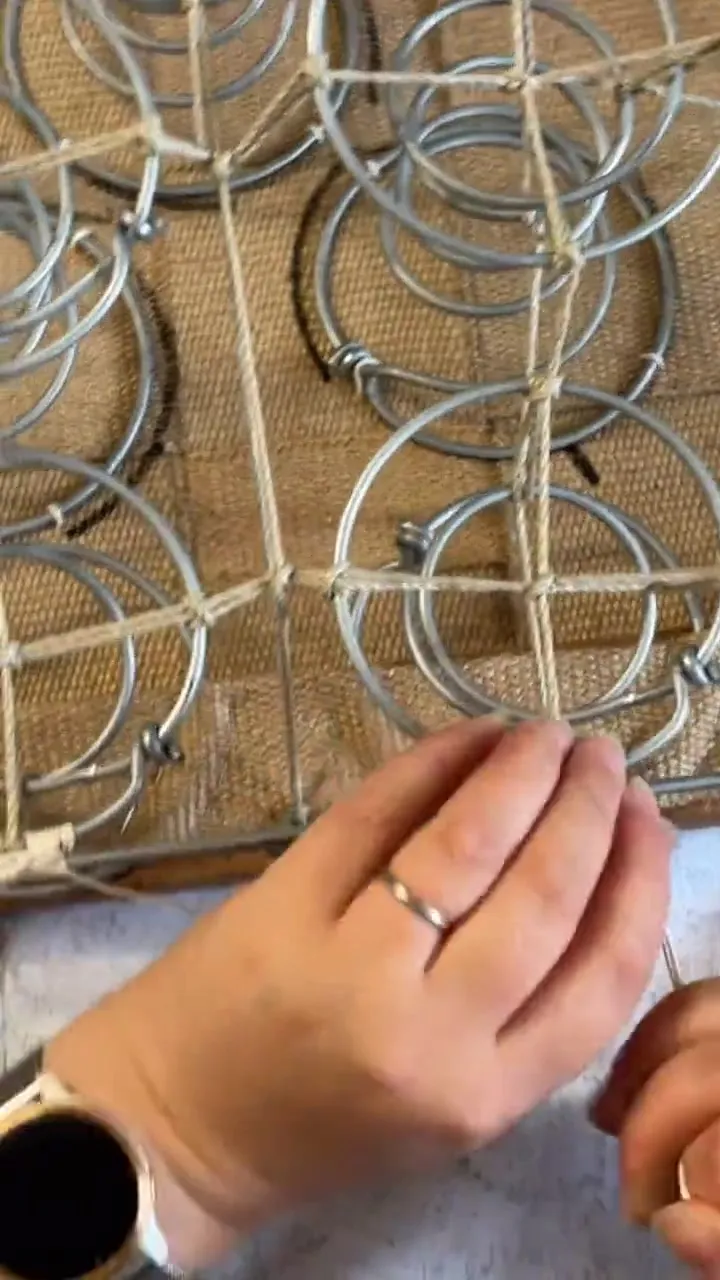 Mains nouant la corde à guinder sur les ressorts d’une assise posée sur sa toile de jute
