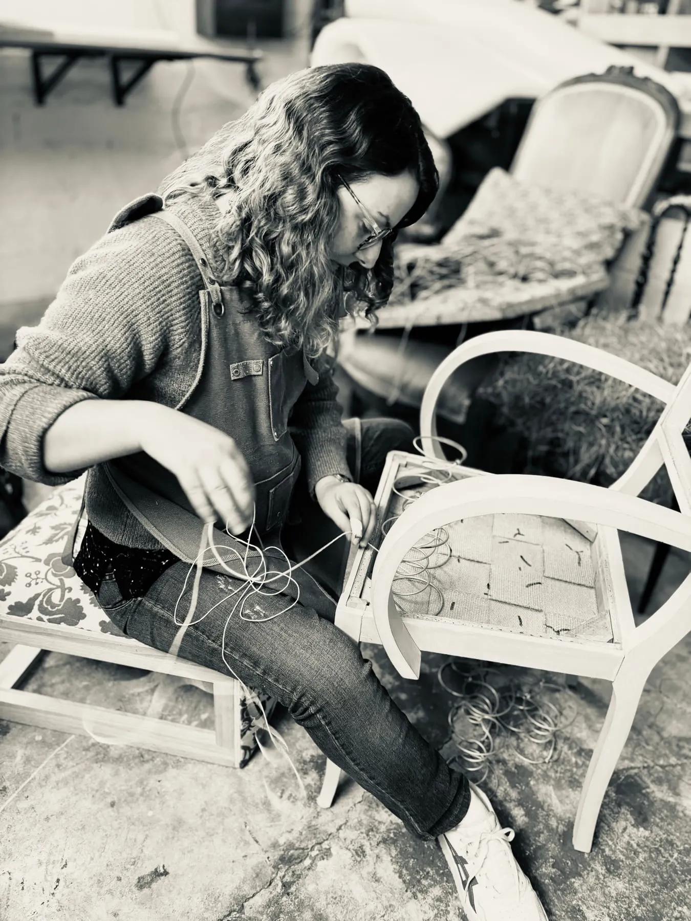 Perrine Wisniewski cousant les ressorts d’un fauteuil sur les sangles