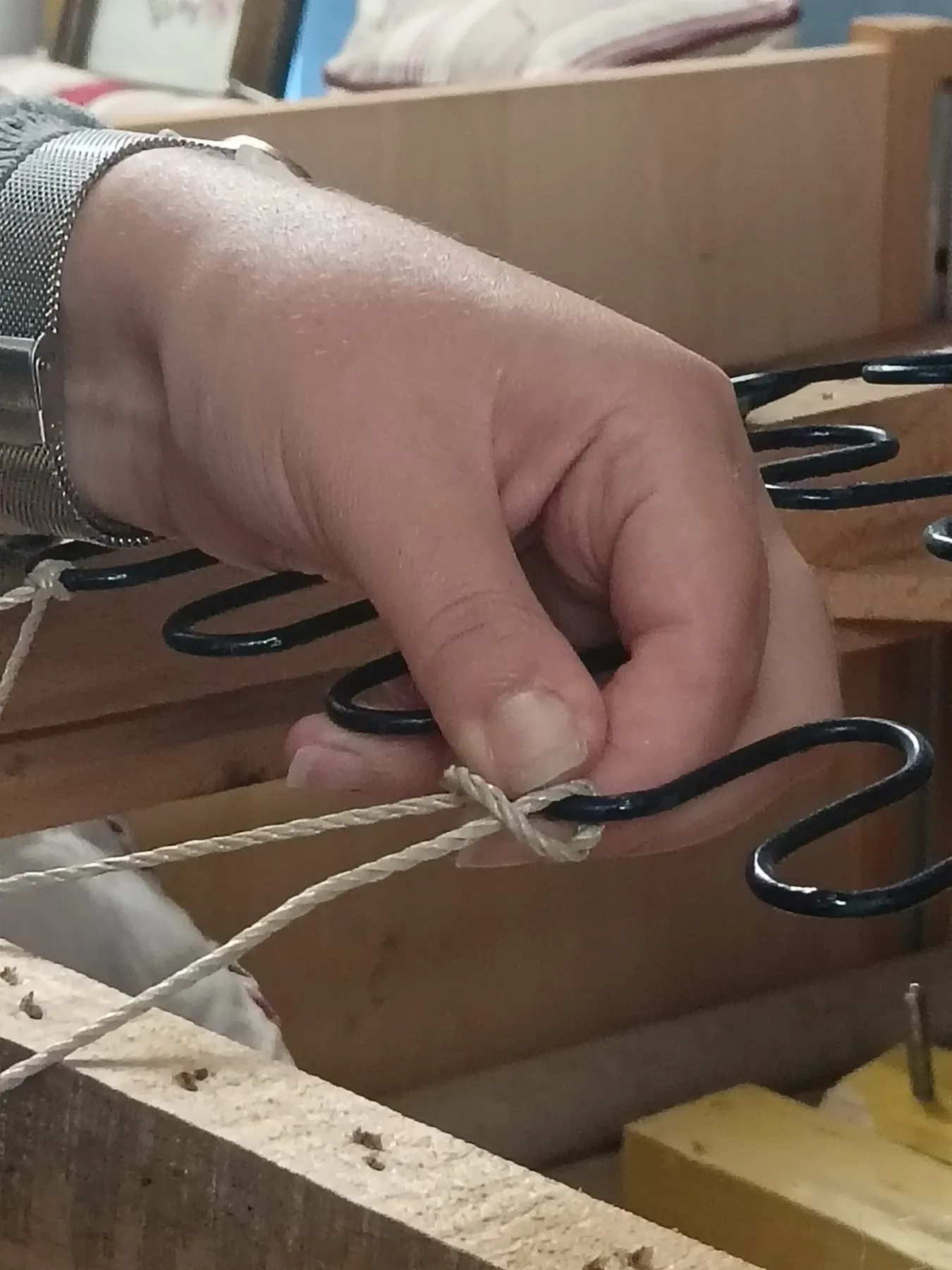 Main du tapissier positionnant un ressort sur une carcasse