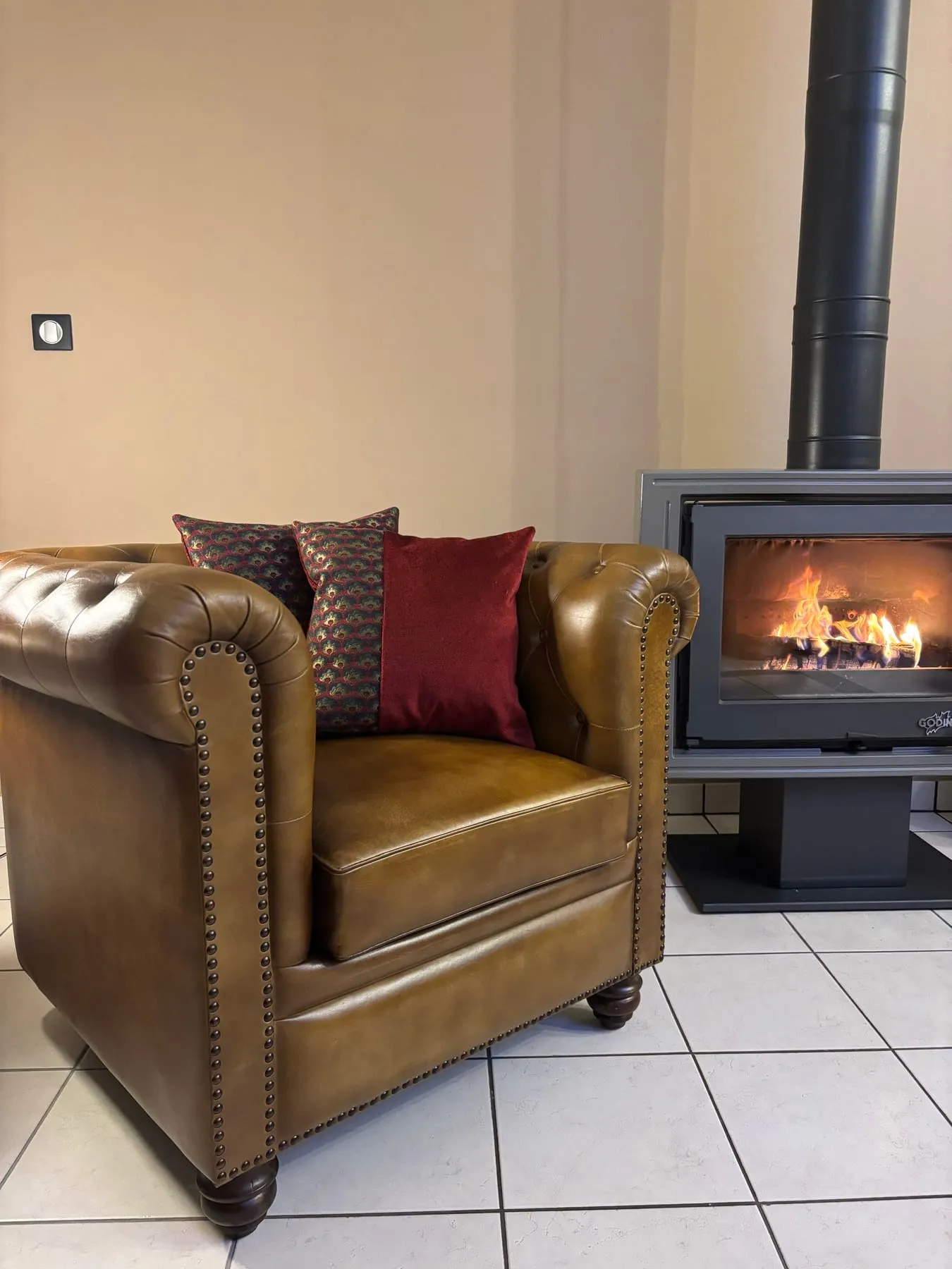 Canapé en cuir fauve agrémenté de coussins sur mesure au coin du feu